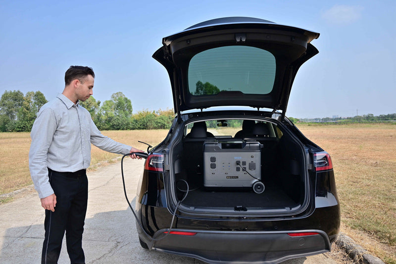 Man charging electric car with portable power station outdoors